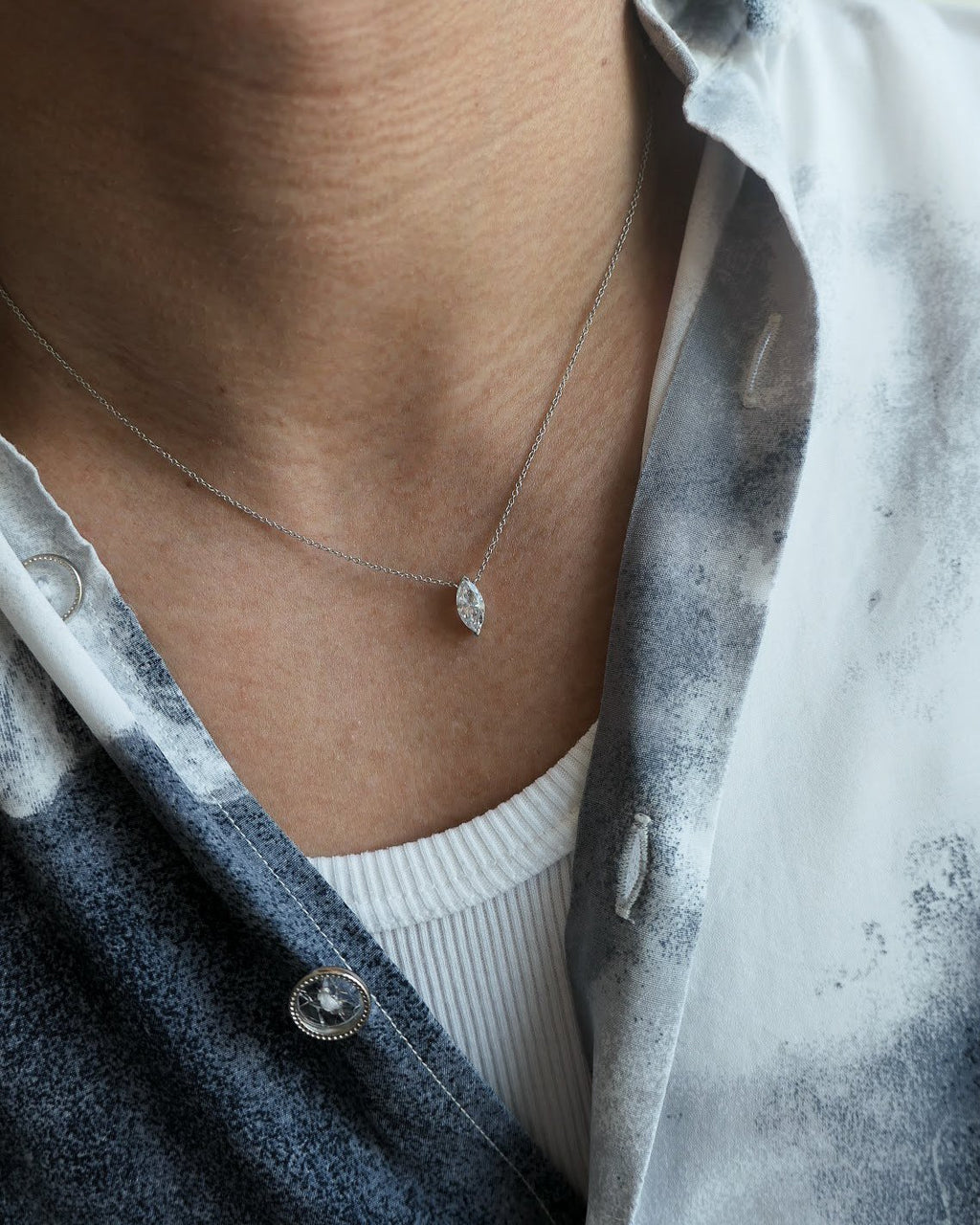man neck down in a grey patterned button down shirt with a white tank top underneath, wearing an 18k white gold diamond marquise necklace