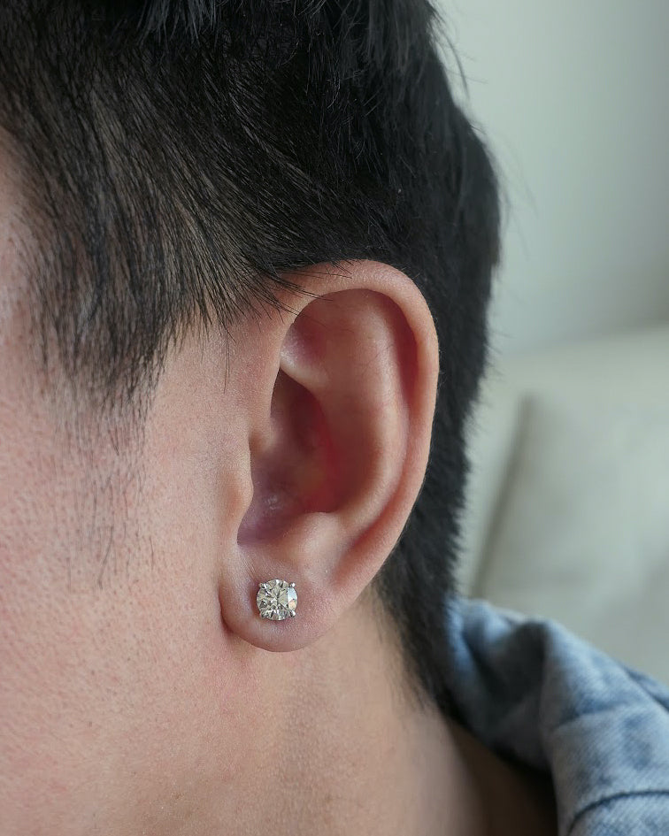 closeup of man's ear, wearing a denim jacket, ear has one 18k white gold diamond stud on it
